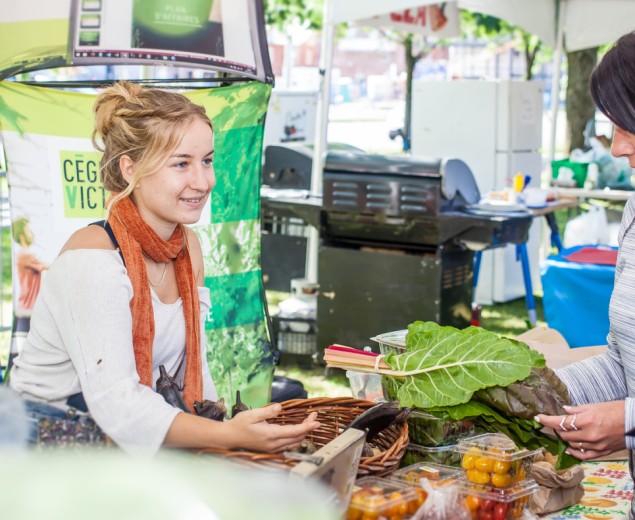 Jeune femme faisant la vente des légumes de la ferme-école du Cégep de Victoriaville dans un kiosque extérieur